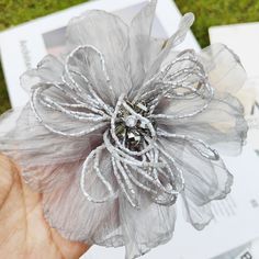 a person is holding a flower made out of organine and beads in their hand