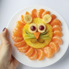 a white plate topped with sliced oranges and an animal face made out of fruit