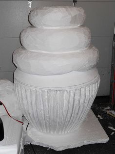 a large white vase sitting on top of a table next to a pile of paper towels