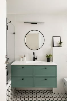 a bathroom with black and white tile flooring and green cabinetry on the wall