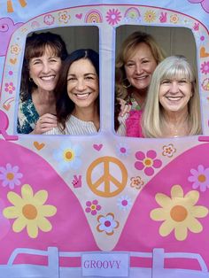 three women are posing in the window of a bus decorated with flowers and peace signs