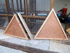 two pieces of wood sit on the ground in front of a building with chicken cages