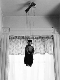 a man hanging from the ceiling in front of a window