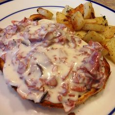 a white plate topped with meat covered in gravy next to french fries and potato wedges