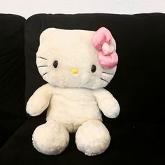 a hello kitty stuffed animal sitting on top of a black couch with a pink bow