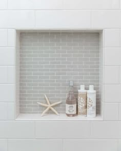 a white brick fireplace with two bottles and starfish on the shelf next to it