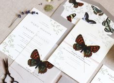 the wedding stationery is decorated with butterflies