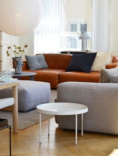 a living room with couches, tables and lamps on the wall in front of windows