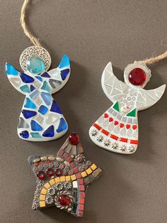 three christmas ornaments hanging from strings on a counter top, one with an angel ornament and the other decorated with glass beads