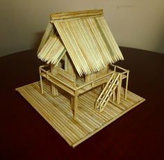 a house made out of bamboo sitting on top of a wooden table next to a wall