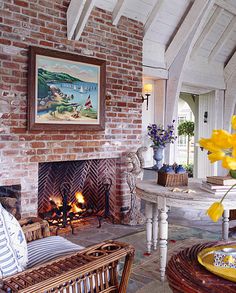 a living room filled with furniture and a fire place in front of a brick wall