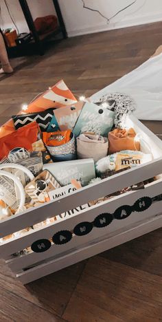 a white box filled with assorted items on top of a wooden floor next to a table