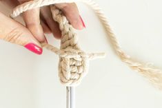 a woman's hand pulling the end of a crochet knot onto a hook