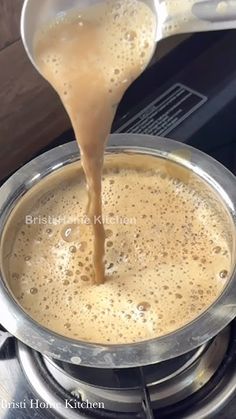 a person pouring liquid into a pot on top of a stove