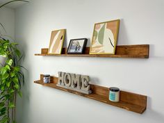 two wooden shelves with pictures on them and some candles in front of the sign that says home