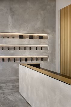 an empty counter with candles on it in front of a gold and white wall mounted shelf