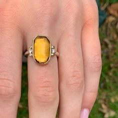 Like a little ray of sunshine on your finger. This vibrant citrine is set in 14k gold atop a handmade sterling silver band. Flanked by brilliant white diamonds. Approx stone size: 16mm x 10mm Approx ct weight: 5.95cts Mohs Hardness: 7 This one of a kind piece is handmade to in Emily's Hudson Valley studio. This piece is in stock and can be resized prior to shipping. If you have questions about sizing, shipping or need help deciding please reach out to us! Luxury Yellow Gold Topaz Ring In Sterling Silver, Sterling Silver Yellow Gold Topaz Ring With Center Stone, Yellow Diamond Ring With Gemstones In Sterling Silver, Yellow Diamond Ring In Sterling Silver, Gold Topaz Ring In Sterling Silver, Yellow Gold Topaz Ring With Sterling Silver, Yellow Sterling Silver Rings With Diamond Accents, Yellow Gold Sterling Silver Topaz Ring, Fine Jewelry Yellow Gold Topaz Ring In Sterling Silver