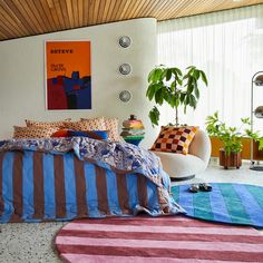 a bed sitting in a bedroom next to a chair and potted plant on top of a rug