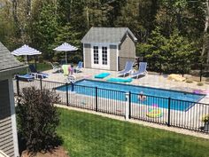 an above ground swimming pool with lounge chairs and umbrellas next to the fenced in area