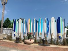 several surfboards lined up against a white fence