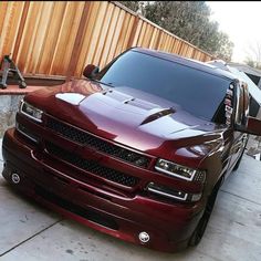 a maroon truck parked in front of a wooden fence