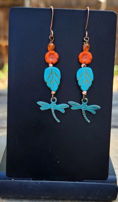 With these dragonfly earrings flying into your life, there is sure to be transformation and joy!  Dragonflies symbolize joy.  These are turquoise patina metal dragonflies that dangle at the end of a string of colorful Czech glass and copper beads.  Love the rich turquoise leaf and tiny orange flower! The dragonfly earrings measure just over 2 1/4 inches in length including the antique copper ear wire hooks.  Just the right earrings for a variety of outfits, from jeans and t-shirt to office attir Adjustable Turquoise Flower Earrings Gift, Turquoise Flower Earrings Gift, Whimsical Turquoise Nickel-free Earrings, Bohemian Hypoallergenic Adjustable Flower Earrings, Patina Metal, Jewelry Nature, Nature Earrings, Dragonfly Earrings, Earrings Turquoise