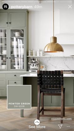 the interior of a kitchen with green cabinets and marble counter tops, along with a gold pendant light