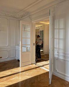 a man is standing in the doorway of an empty room with white walls and wood floors