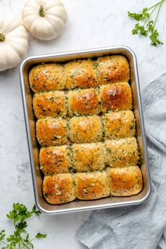 a pan filled with garlic bread rolls and garnished with parmesan sprigs