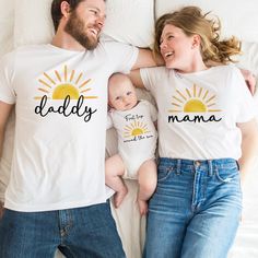 a man and woman laying on top of a bed with their baby wearing matching shirts