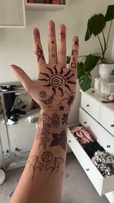 a person's hand with tattoos on it in front of a dresser and mirror