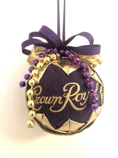 an ornament hanging from a purple ribbon with the word crown royal on it