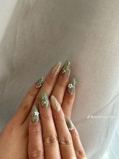 a woman's hands with gold and silver nail polish on her nails, while she is wearing a white shirt