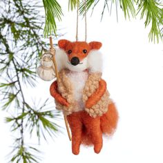 an ornament shaped like a fox hanging from a pine tree with a white background