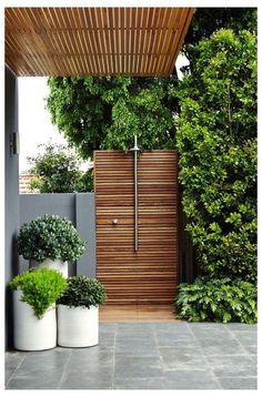 two large white planters sitting in front of a wooden wall and fenced area