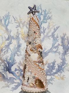 a christmas tree made out of seashells and pearls on a glass base with a starfish