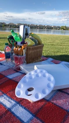 a picnic table with food and drinks on it near the water's edge,