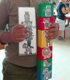 a person holding up a stack of blocks with pictures on them