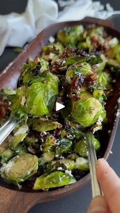 a person is holding a spoon over a bowl of brussel sprouts