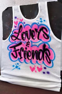 Designs by Galveston Airbrush! ♡ Feel free to contact me with any questions or custom orders.  ✧ Our Designs on these cute White beater Tank tops are handmade with the artists' skilled Hands. The Design might look slightly different from the pictures or have small imperfections and that's okay, it's what makes them unique✧ Each design includes up to TWO names or words with up to THREE specified COLORS. SIZES: Available for ADULTS and YOUTH DESIGN PLACEMENT: All designs are airbrushed on the FRON Customizable Sleeveless Tops, Airbrush Shirt Ideas, Wife Beater Tank, White Ribbed Tank Top, Airbrush Shirts, Airbrush T Shirts, Airbrush Designs, 21st Birthday Photoshoot, Custom Airbrushing