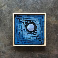 a blue and black square with a hole in the middle on a concrete wall background