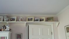 the shelves above the door are filled with pictures and photos, including teapots