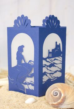 a card with an image of a woman riding a horse on the beach next to a seashell