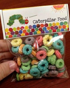 a person holding up a bag of colorful donuts in front of a caterpillar food card