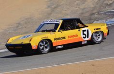 a yellow sports car driving down a race track