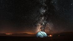 a tent is set up in the middle of a field under a night sky filled with stars