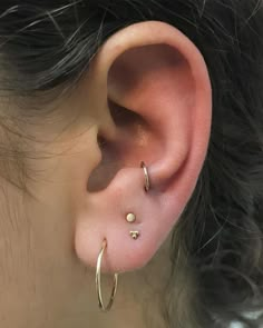 a close up of a person's ear with two small gold hoops on it