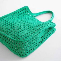 a green crocheted bag sitting on top of a white table