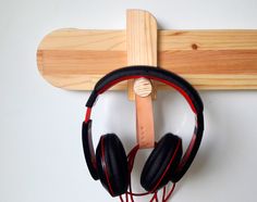 headphones are hanging on the wall with a wooden cross in the background and red cords attached to it