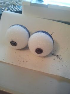 two white balls with black spots on them sitting on a piece of paper next to a window